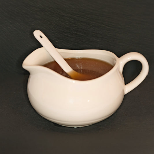 A white pitcher and spoon, with pastured chicken stock