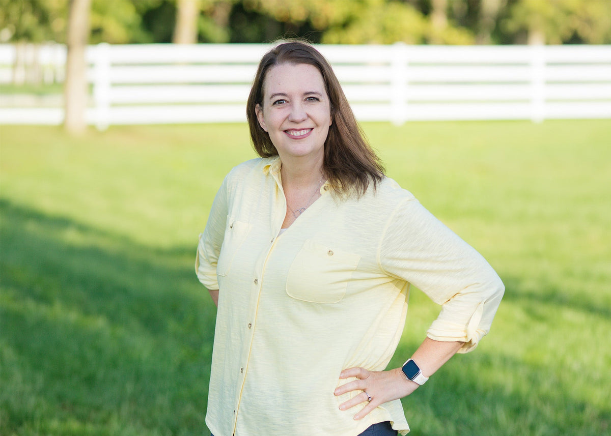 Shannon Perlow, posing in front of a grassy field and white fence.